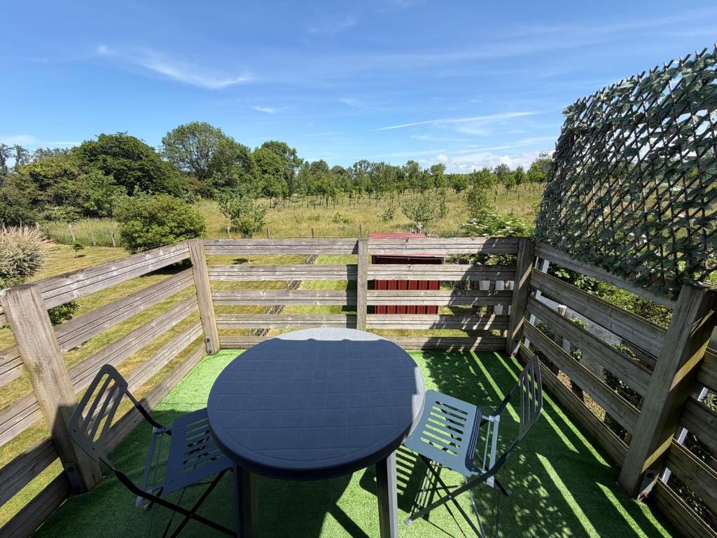 a table and chairs on a deck with a fence at Le chant des oiseaux chambre pour deux à quelques minutes de la Baie de Somme entre nature mer et télétravail in Nibas