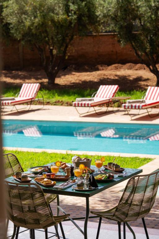 a table with food on it next to a swimming pool at Palais Zaitunay in Marrakesh
