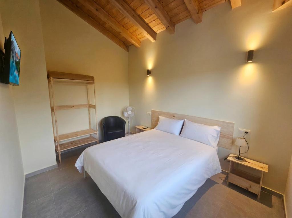 a bedroom with a white bed and a chair at Hostal JP y Estudios in Sangüesa