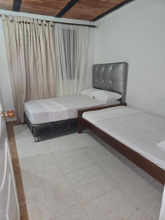 two beds sitting in a room with curtains at Finca la santa in San Luis de Cubarral