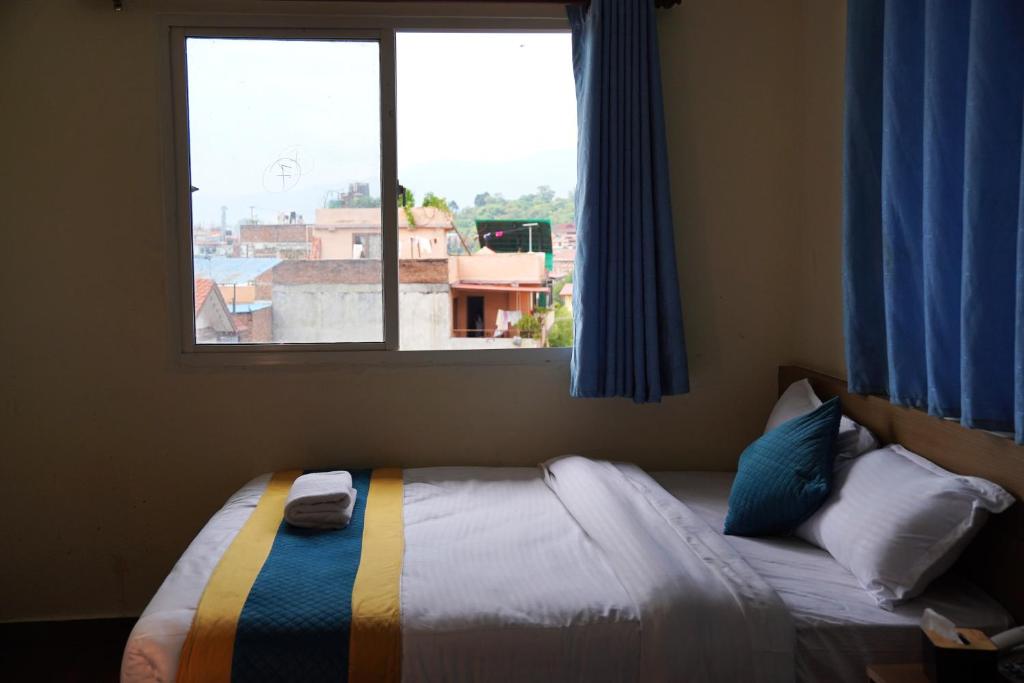 a bedroom with a bed and a window with blue curtains at Hotel Kusum Palace in Kathmandu