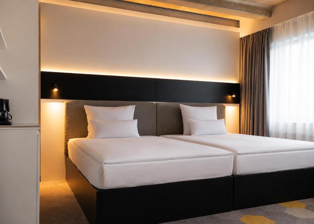 a bedroom with a white bed with a black headboard at Olive INN Berlin in Berlin