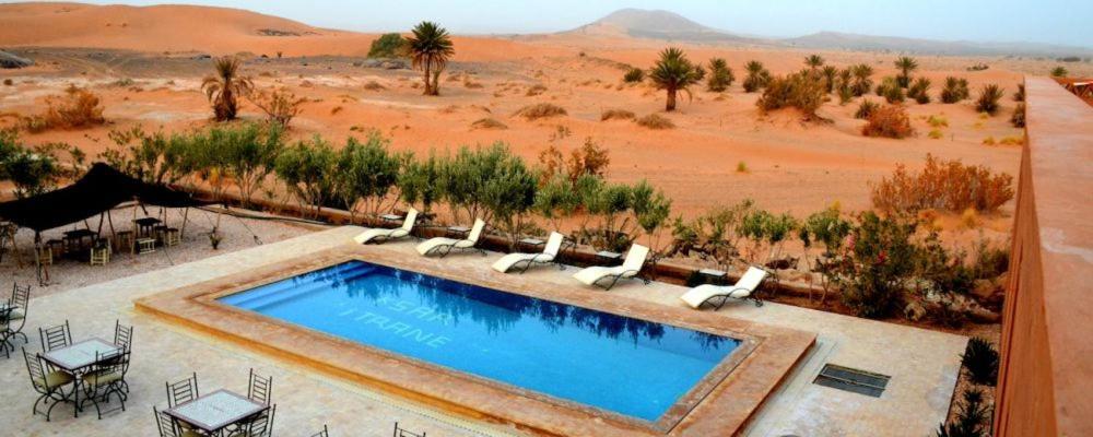 a swimming pool in the middle of the desert at Itrane sahara Auberge in Taouz