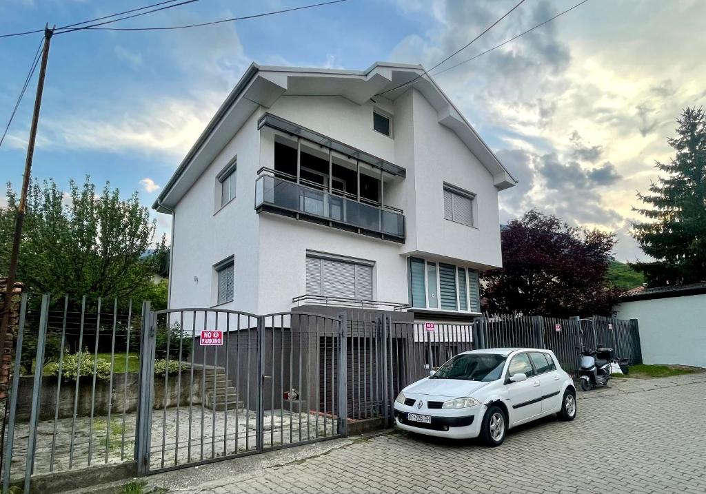 a white car parked in front of a white house at Cozy Home in Peje