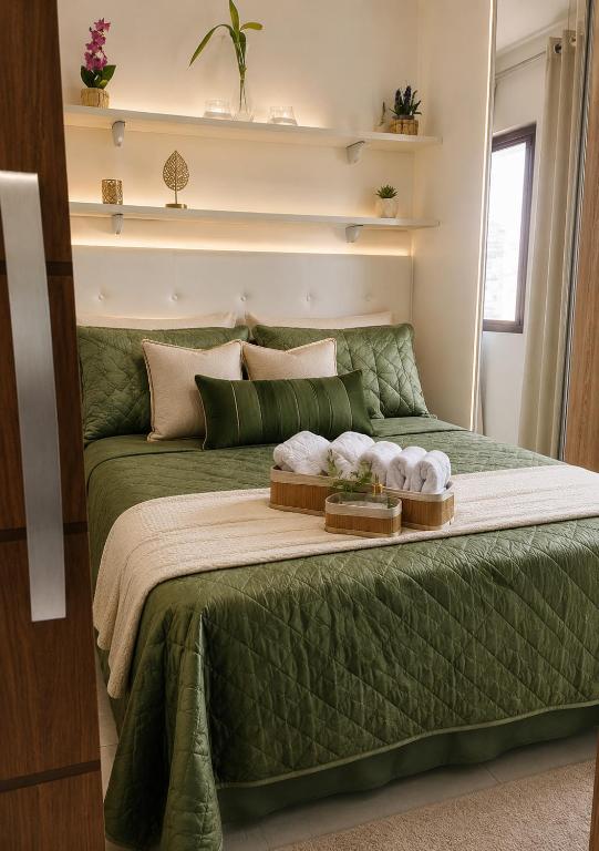 a green bed with two towels on top of it at Apê Panoramic Águas Claras e Ministérios in Brasília
