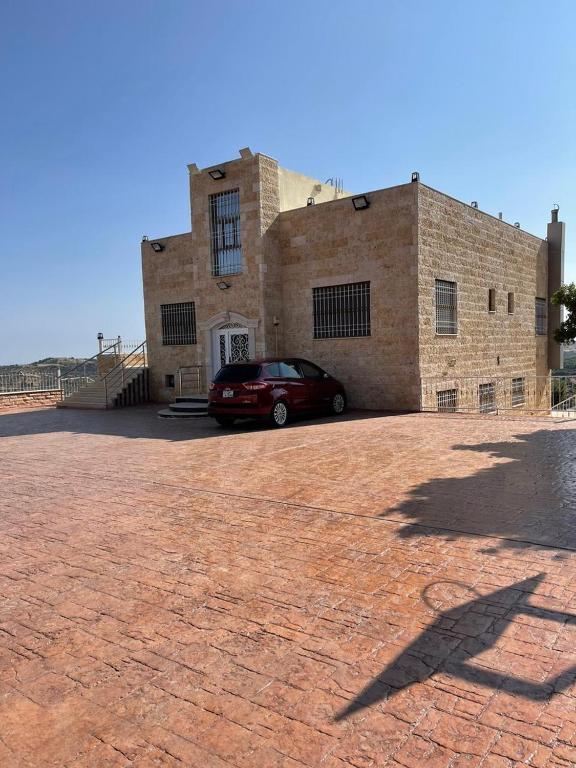 a car parked in front of a brick building at جبال جرش in Jerash
