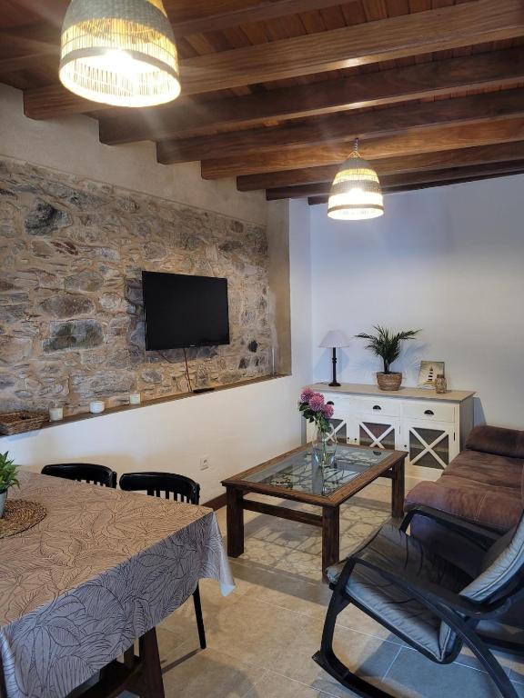 a living room with a table and a tv on a wall at Casa Rivendell in Ladrido