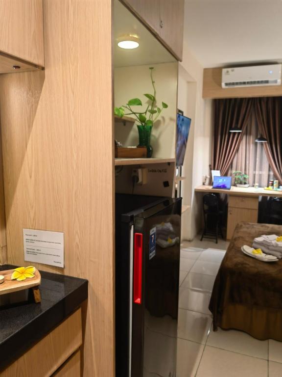 a small refrigerator in a room with a bedroom at Studio Pleasant Tifolia in Jakarta