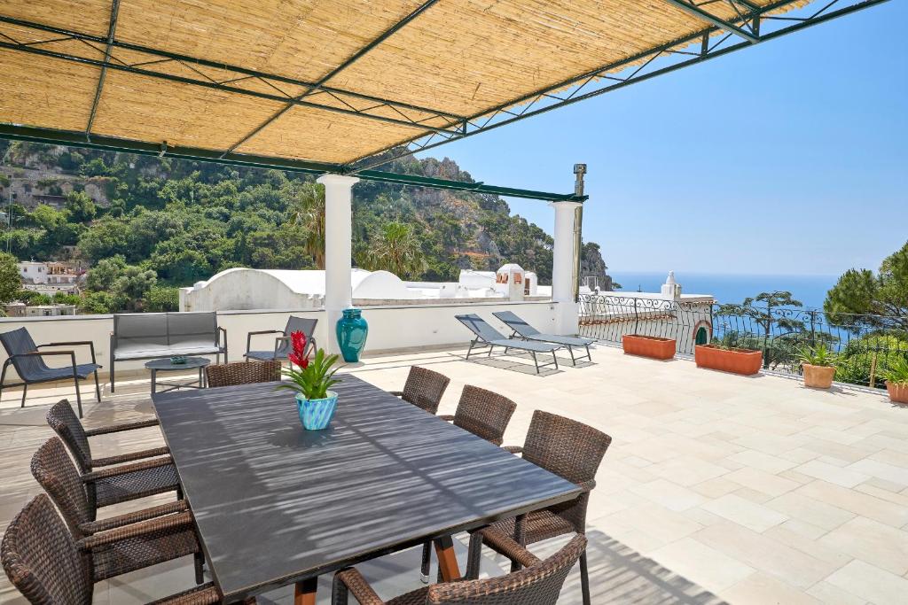 a patio with a table and chairs on a roof at La Marilena Penthouse in Capri