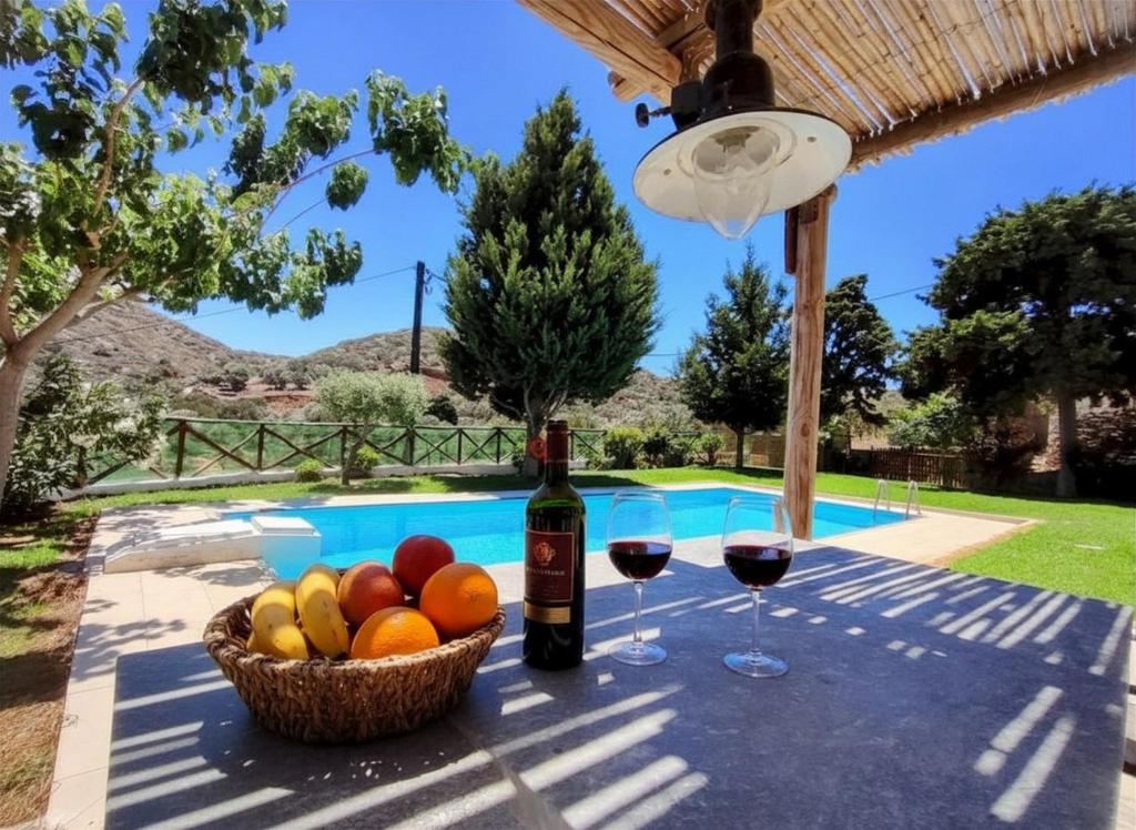 a table with wine glasses and fruit next to a pool at Elounda Collection Villa in Vrouchas