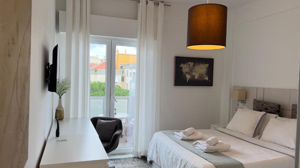 a bedroom with a bed and a desk and a window at Quarto com casa de banho privativo in Amadora