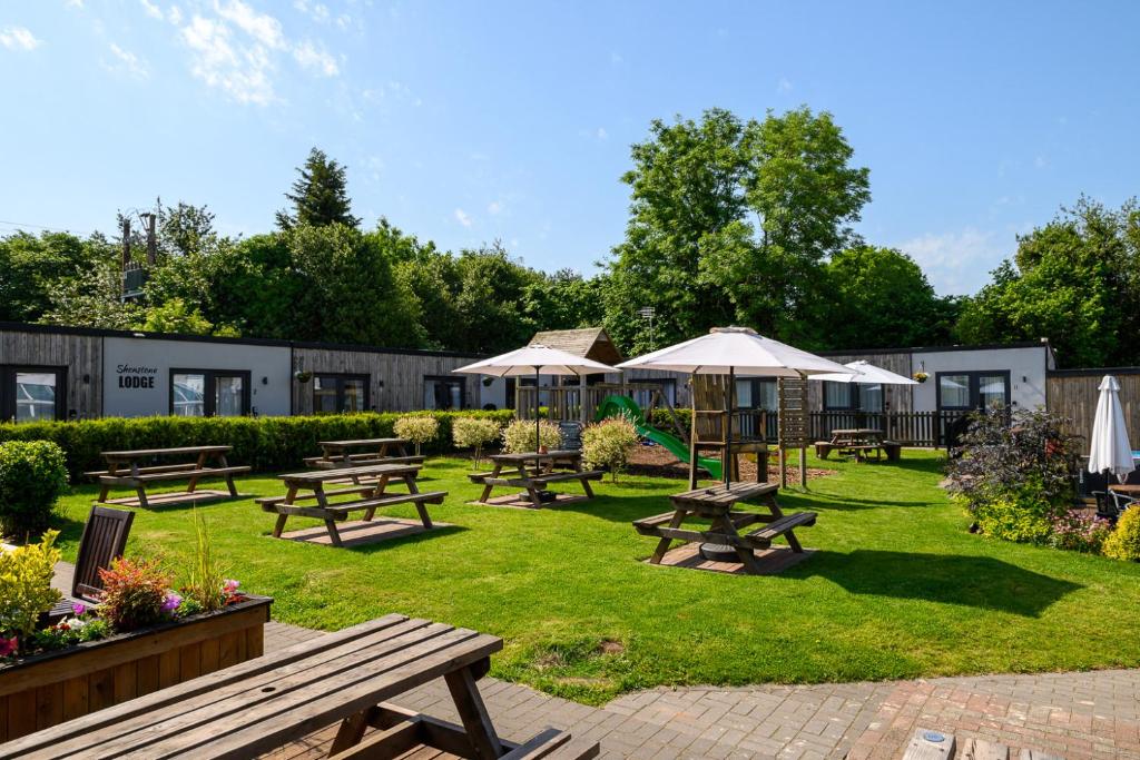 a group of picnic tables and umbrellas in a park at Shenstone Lodge in Kidderminster