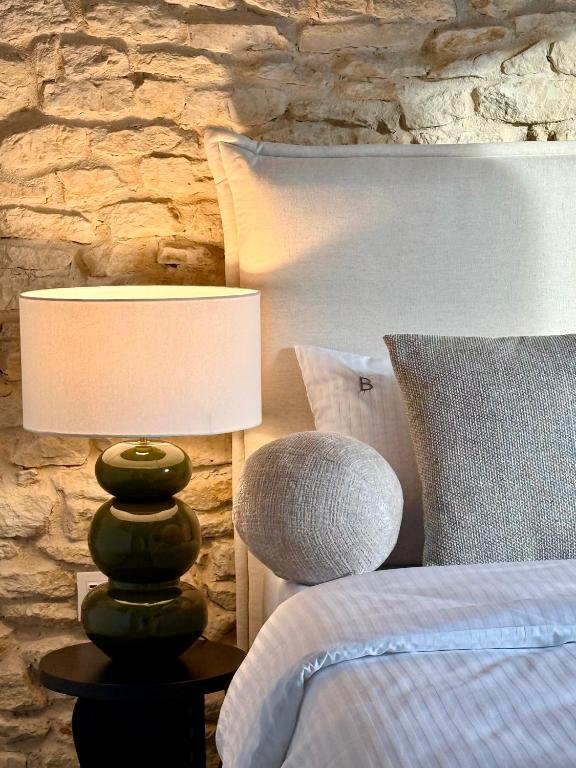 a bed with a lamp next to a stone wall at BOGORIA Apartments in Uniejow