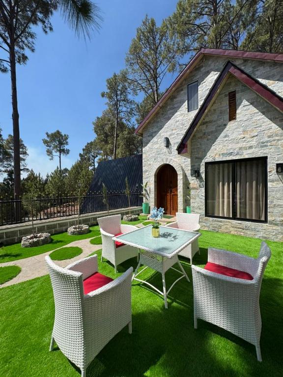 a patio with a table and chairs in front of a building at Swiss Chalet Near Murree in Bhāngal