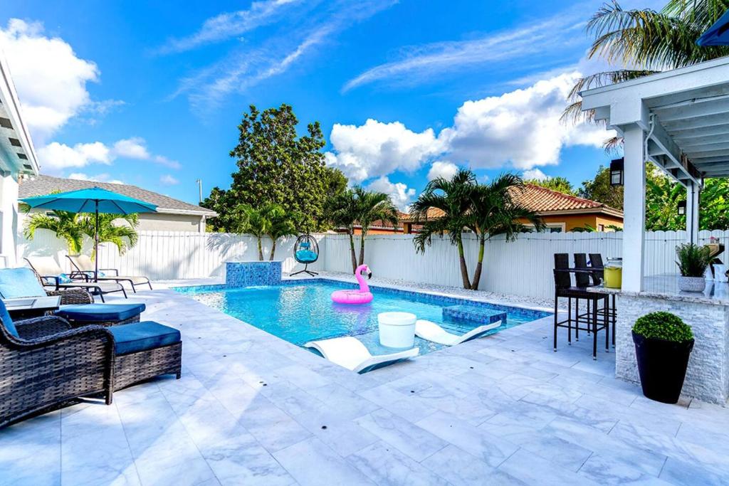 a swimming pool with chairs and a pink pool noodle in a backyard at Heated Pool Family Retreat- Games, Everglades, Keys in Miami