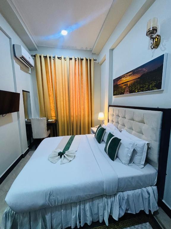 a bedroom with a large white bed and a window at Diary Hotel in Dar es Salaam