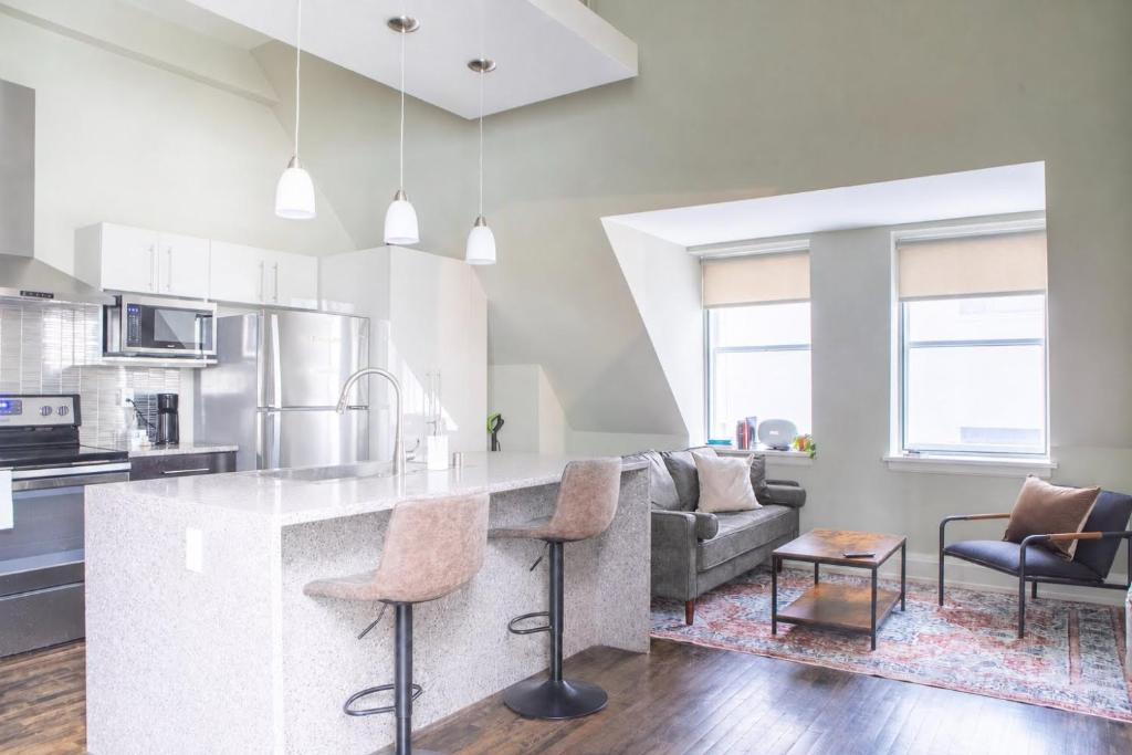 a kitchen and living room with a counter and chairs at Downtown Luxury 1BR Loft · Walkable · Sleeps 4 in Milwaukee