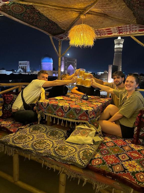 a group of people sitting around a table with mats at LAYALI boutique TERRACE & Café in Bukhara