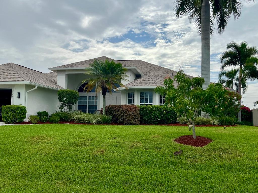 a house with a palm tree in a yard at Villa Tortuga - Place to Relax in Cape Coral