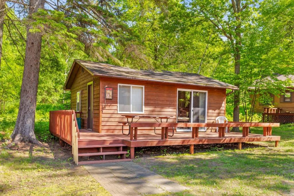 a log cabin with a large deck and a bench at Cabin #10 2BR 1BA Timberlane Resort in Park Rapids
