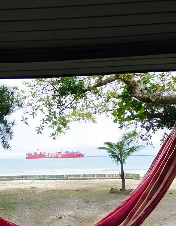 a hammock with a cruise ship in the water at Chalé frente mar na Ilha do Mel - Encantadas. in Ilha do Mel
