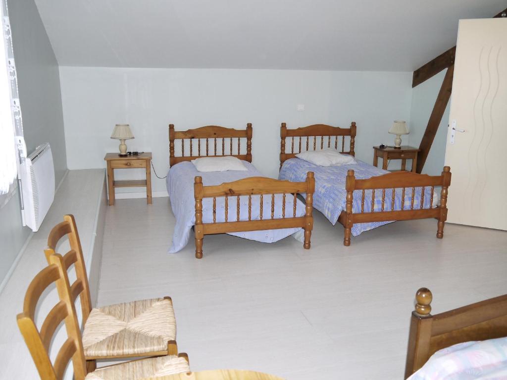 a bedroom with two beds and two chairs at Gîte Beaupel in Neuvy-en-Mauges