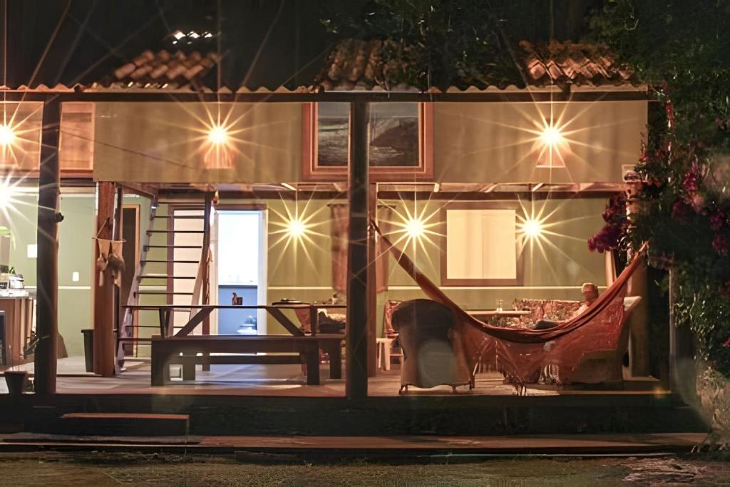 a person sitting in a hammock on a patio at night at Casa da Ale e do Thi - Ilha do Mel in Ilha do Mel