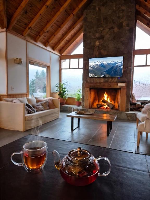 a living room with a fireplace and a tea pot on a table at Hostería Bärenhaus in San Martín de los Andes