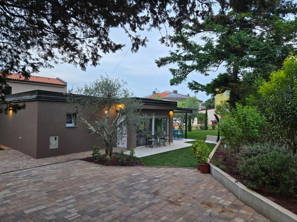 a house with a brick driveway in front of a yard at Holiday House Altea in Banjole