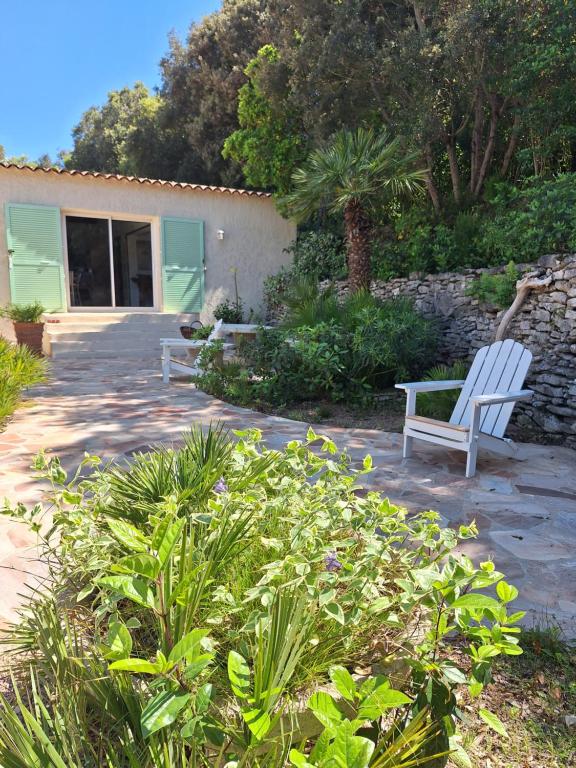 two white benches sitting on a patio in a garden at Gîte Acellu in Bonifacio