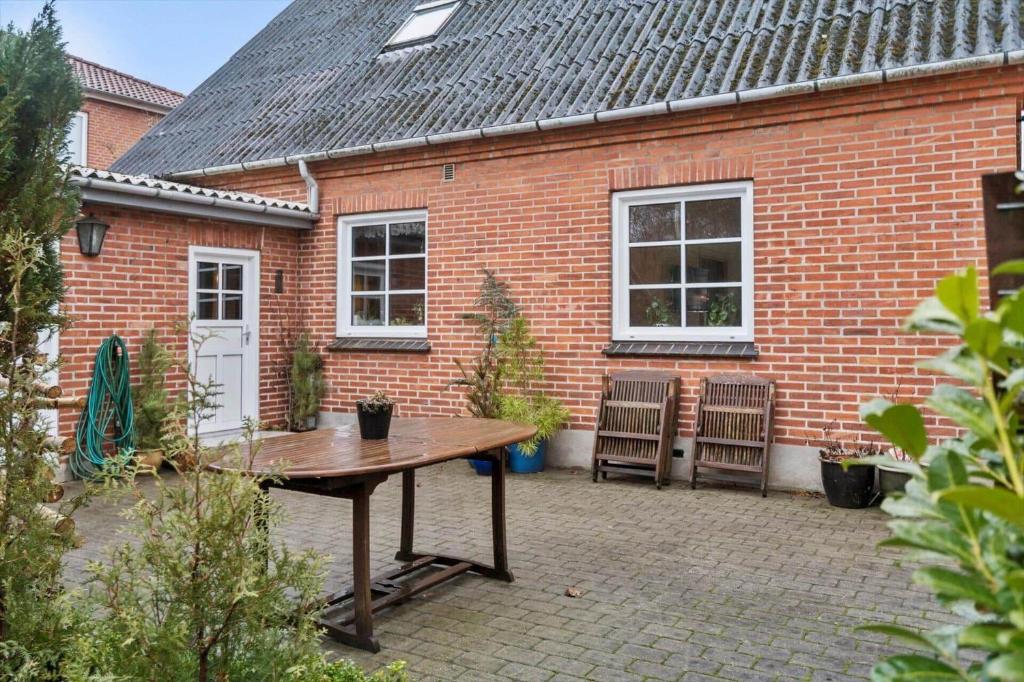 a patio with a table and two chairs in front of a brick building at 80320-Ulfborg-Reberbanen-4 in Ulfborg