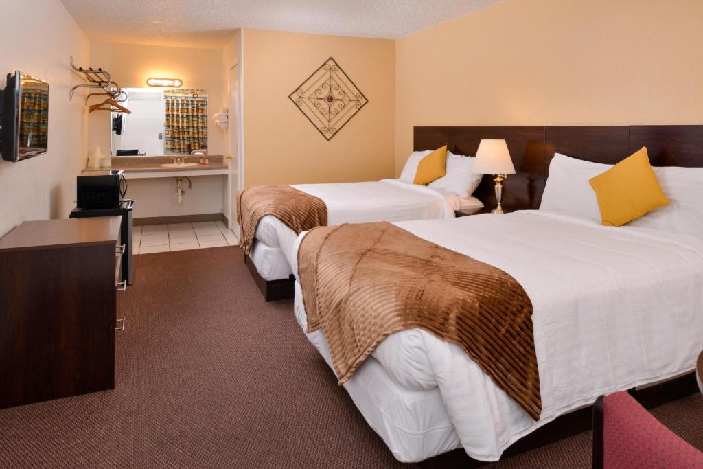 a hotel room with two beds and a television at Red Carpet Inn Battleboro in Battleboro