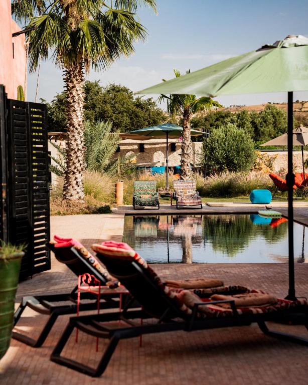 two lounge chairs and an umbrella next to a pool at Casa Misasha, pool & rooftop-5 suites-13 lits-hamam in Essaouira