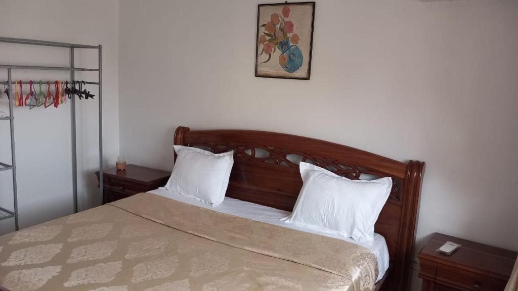 a bedroom with a wooden bed with white pillows at Elite appart in Dakar