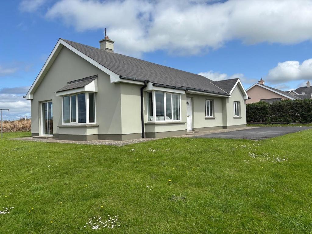a house with a green lawn in front of it at Beach view Bungalow in Spanish Point