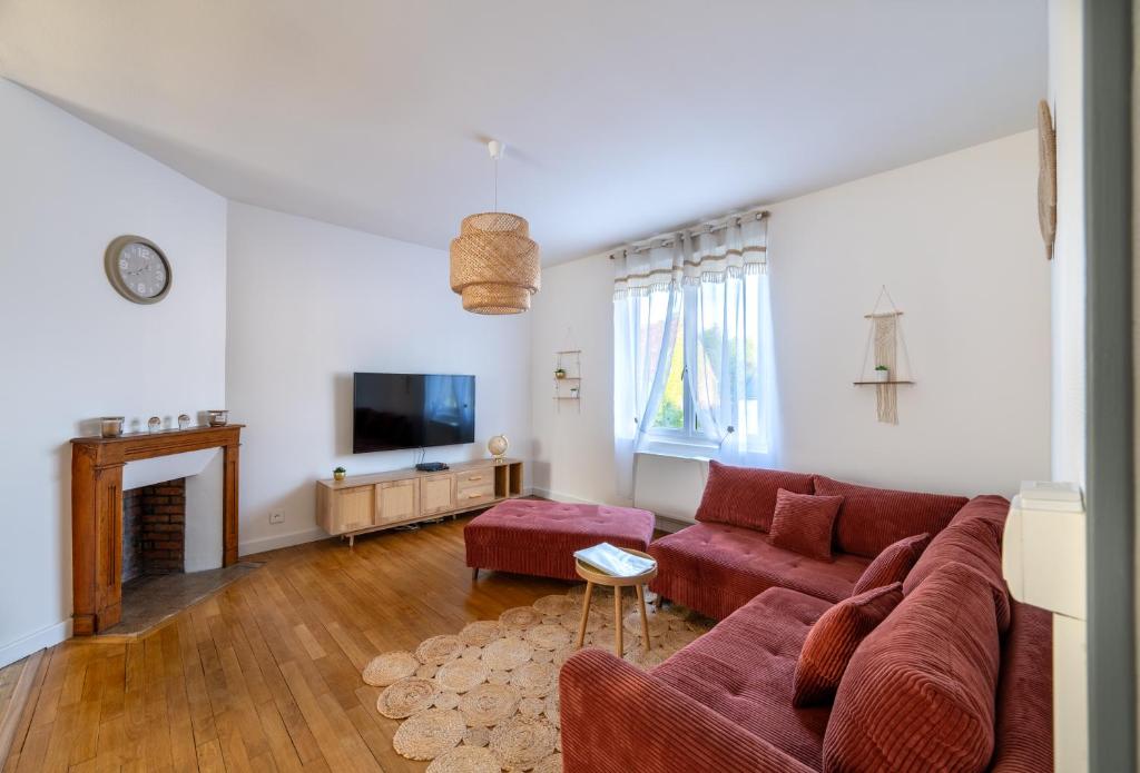 a living room with a red couch and a fireplace at La lande appart in Tranzault