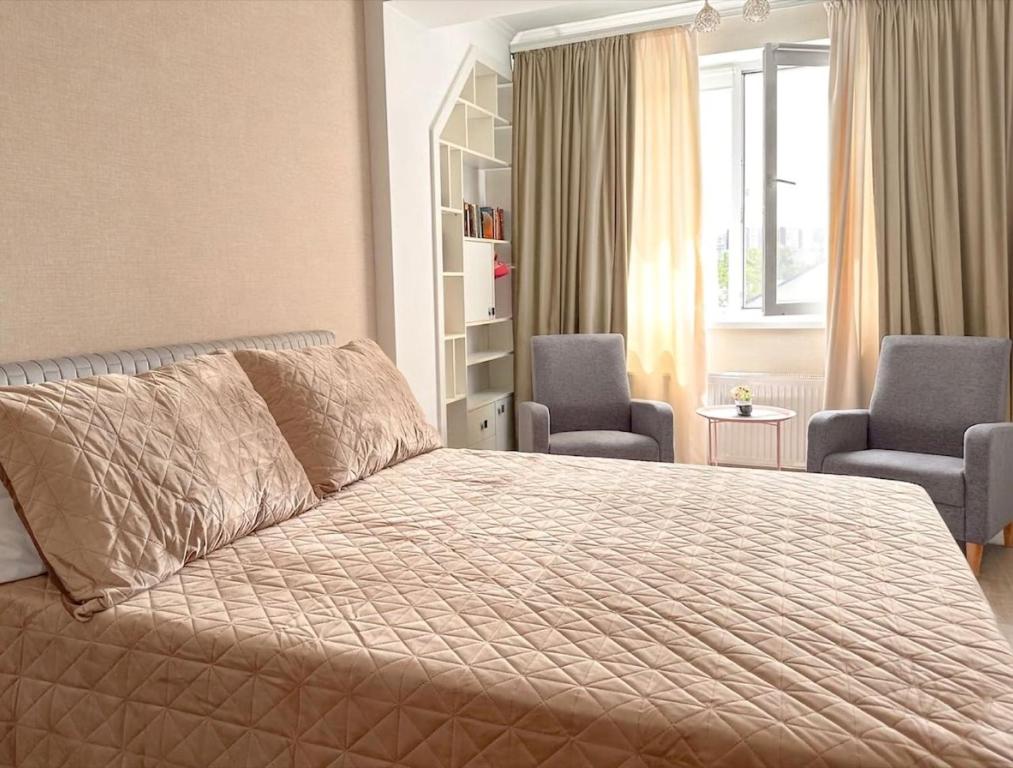 a bedroom with a large bed and two chairs at Central cozy apartments- one and two bedrooms option in Chişinău