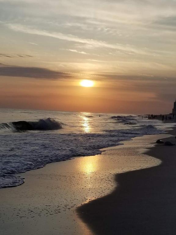 a sunset on a beach with the sun setting at Grand Caribbean in Orange Beach