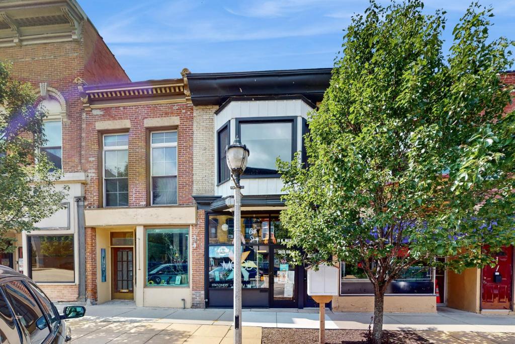 a building on a street with a tree and a street light at Steps to Dtwn & Rock River! Couples Retreat in Janesville