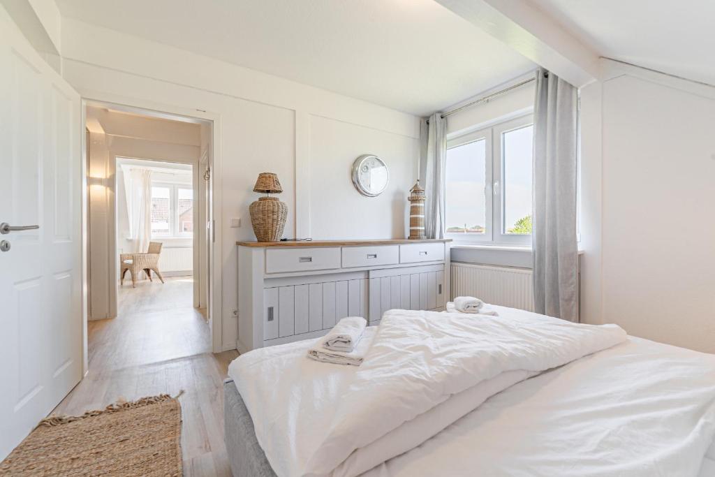 a white bedroom with a bed and a window at Ferienwohnung Deichblick Quartier Pellworm in Pellworm