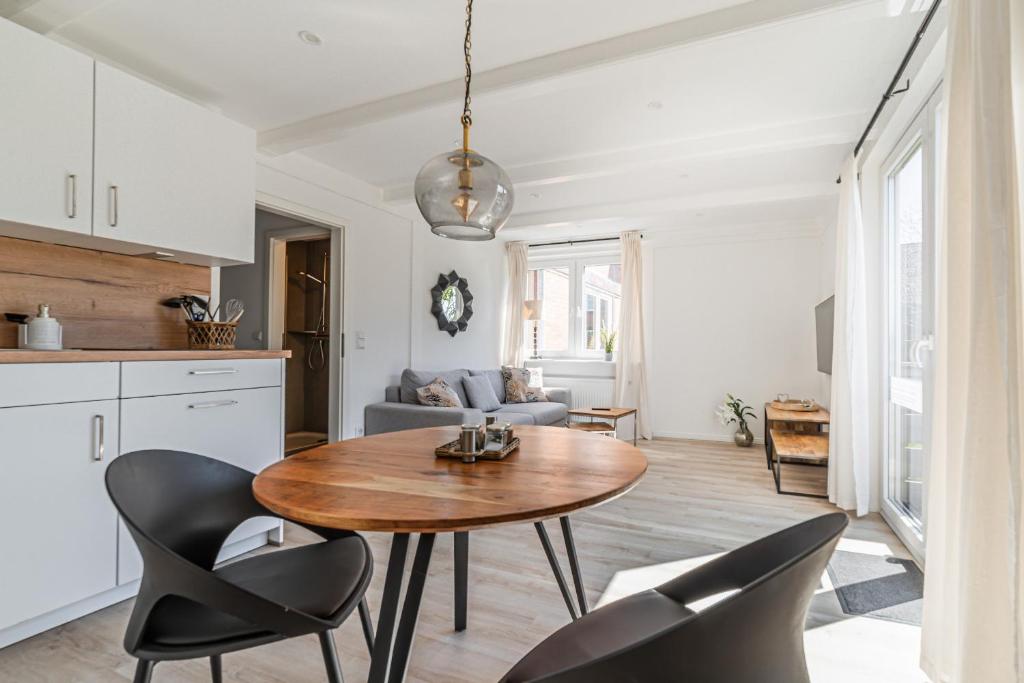 a kitchen and living room with a wooden table and chairs at Ferienwohnung Nordseeheimat Pellworm in Pellworm