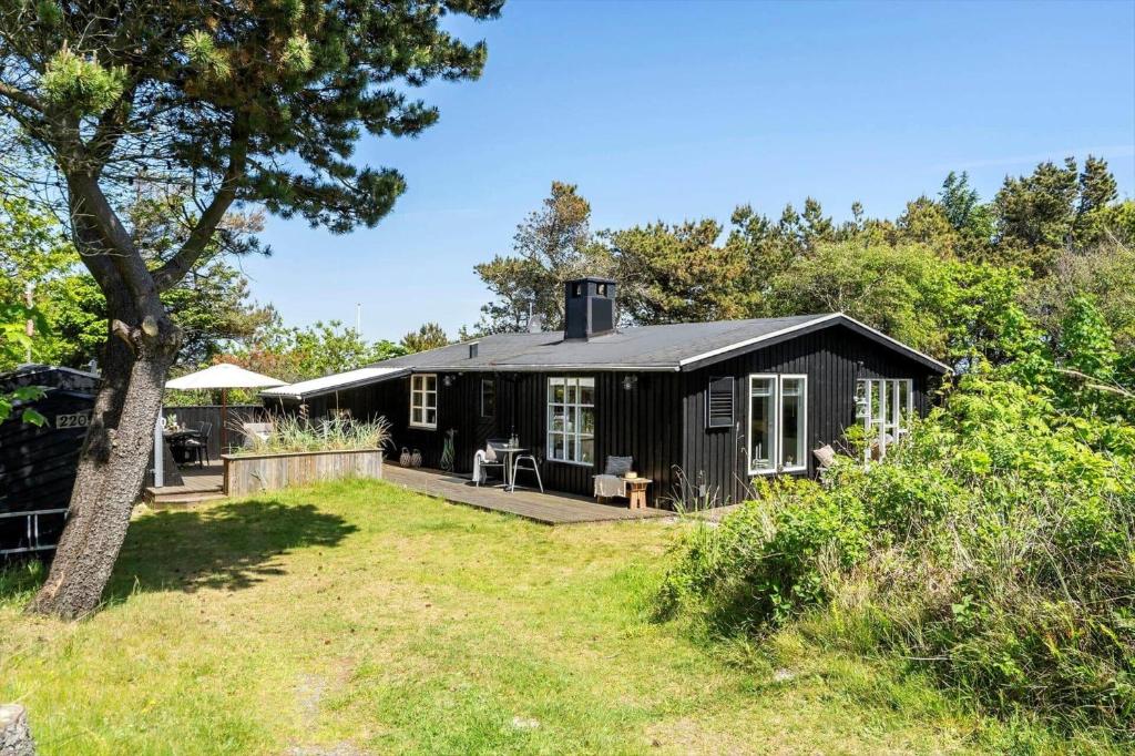 a black cottage with a porch and a yard at 2236-Ringkobing-Fladsbjergvej-220 in Klegod