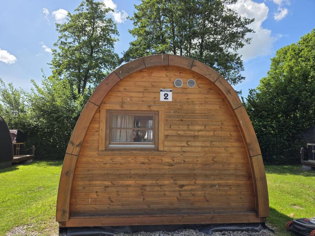 a small wooden building with a window in a yard at 02 Premium Camping Pod "Langeneß" in Silberstedt