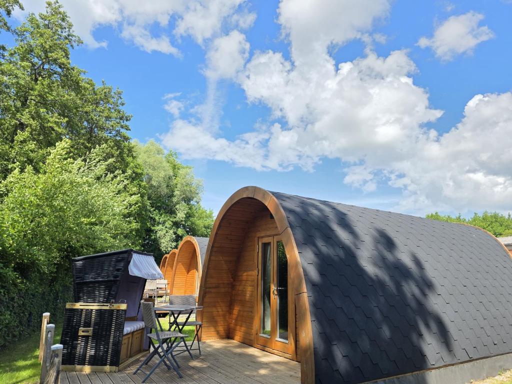 a small wooden house with a deck and a grill at 04 Premium Camping Pod "Oland" in Silberstedt