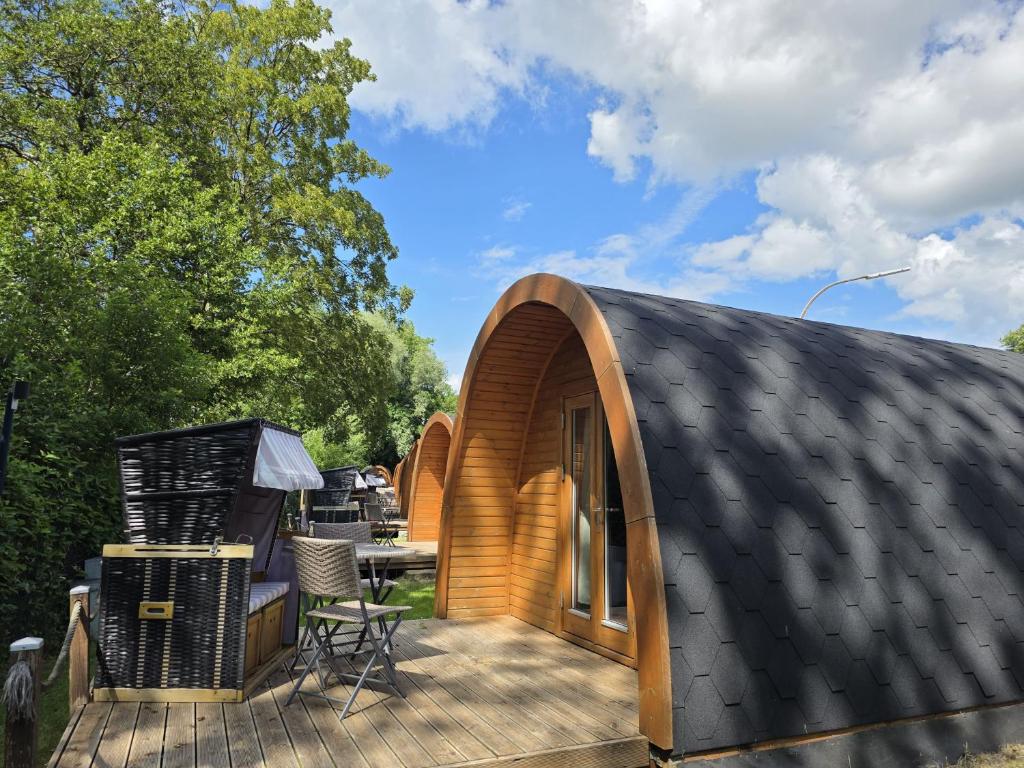 a house with a black roof and a deck at 07 Premium Camping Pod "Norderoog" in Silberstedt