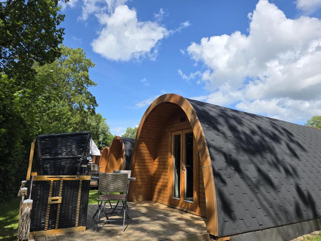 a wooden house with a black roof and a patio at 08 Premium Camping Pod "Süderoog" in Silberstedt