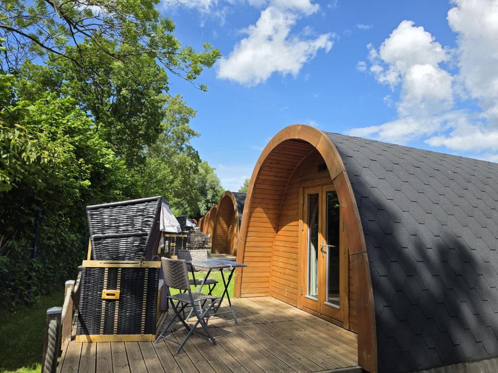 a small wooden cabin with a table and chairs on a deck at 09 Premium Camping Pod "Hambuger Hallig" in Silberstedt
