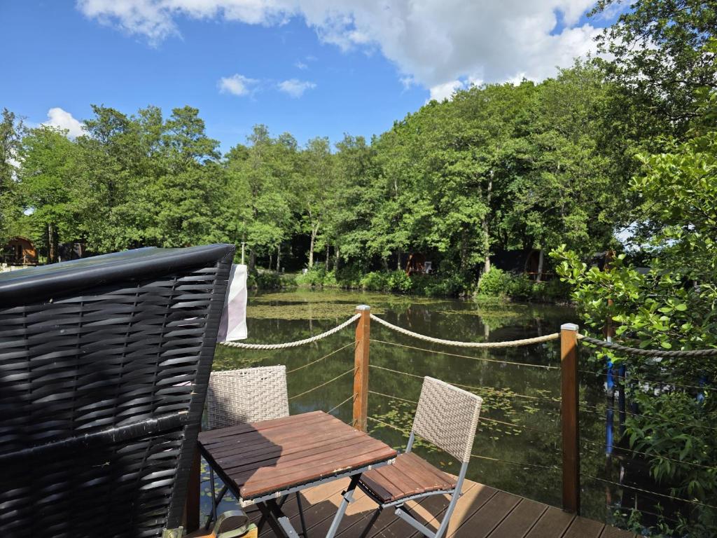 a wooden table and chairs on a deck next to a river at 19 Premium Camping Pod "Alsen" in Silberstedt
