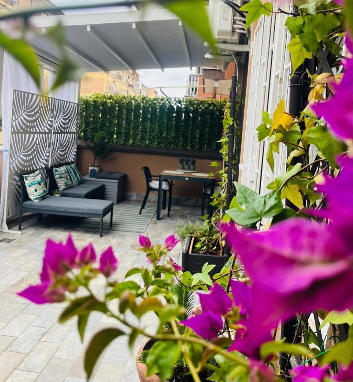 a patio with purple flowers and a couch and a table at ZEFIRO OSTIA-Free parking & Terrace in Lido di Ostia