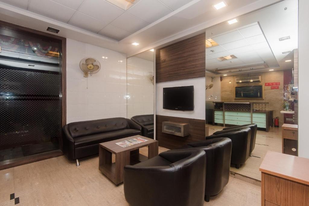 a living room with black leather furniture and a flat screen tv at Super Hotel O Solitaire in Turambhe